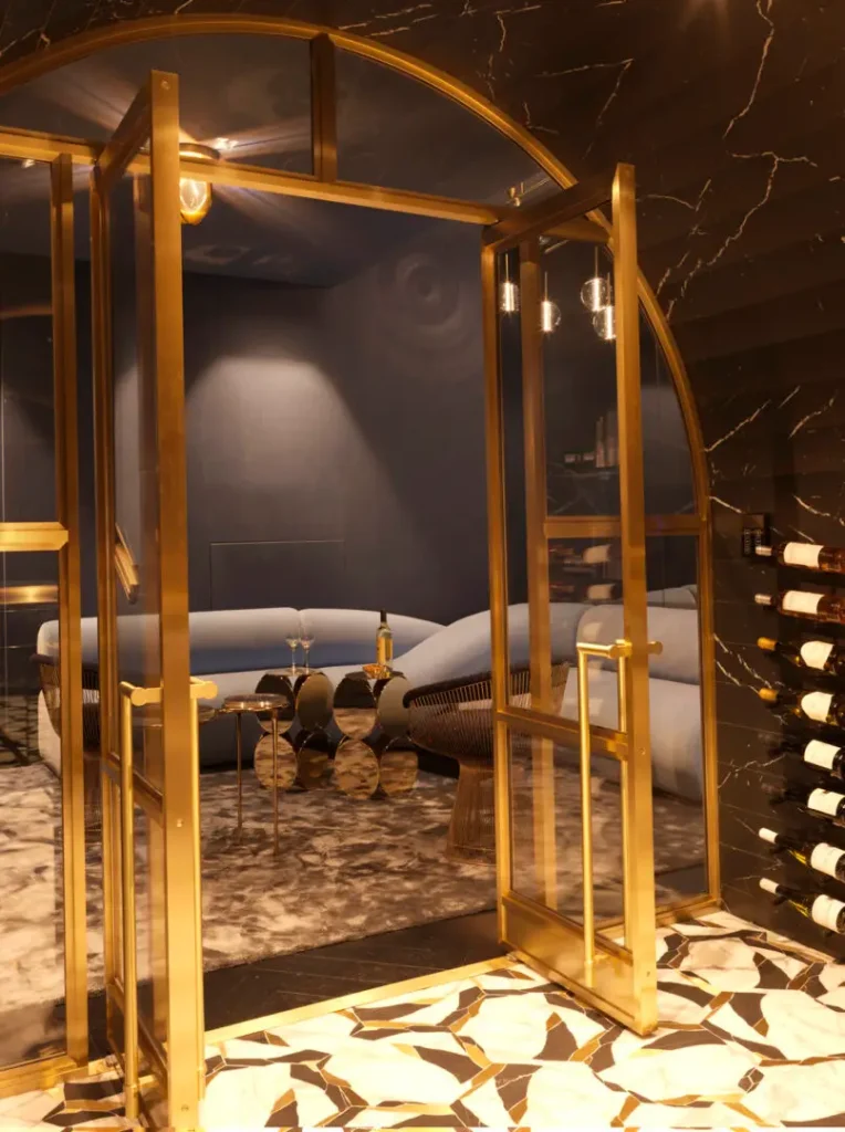 Custom-framed brass and glass wine cellar featuring a hand-fabricated arched marble ceiling by Sculac Homes